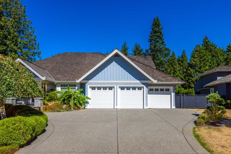 A blue house with a bright blue sky and a new concrete driveway.